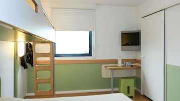 Una habitación pequeña con cama, una ventana, televisor y un taburete verde.