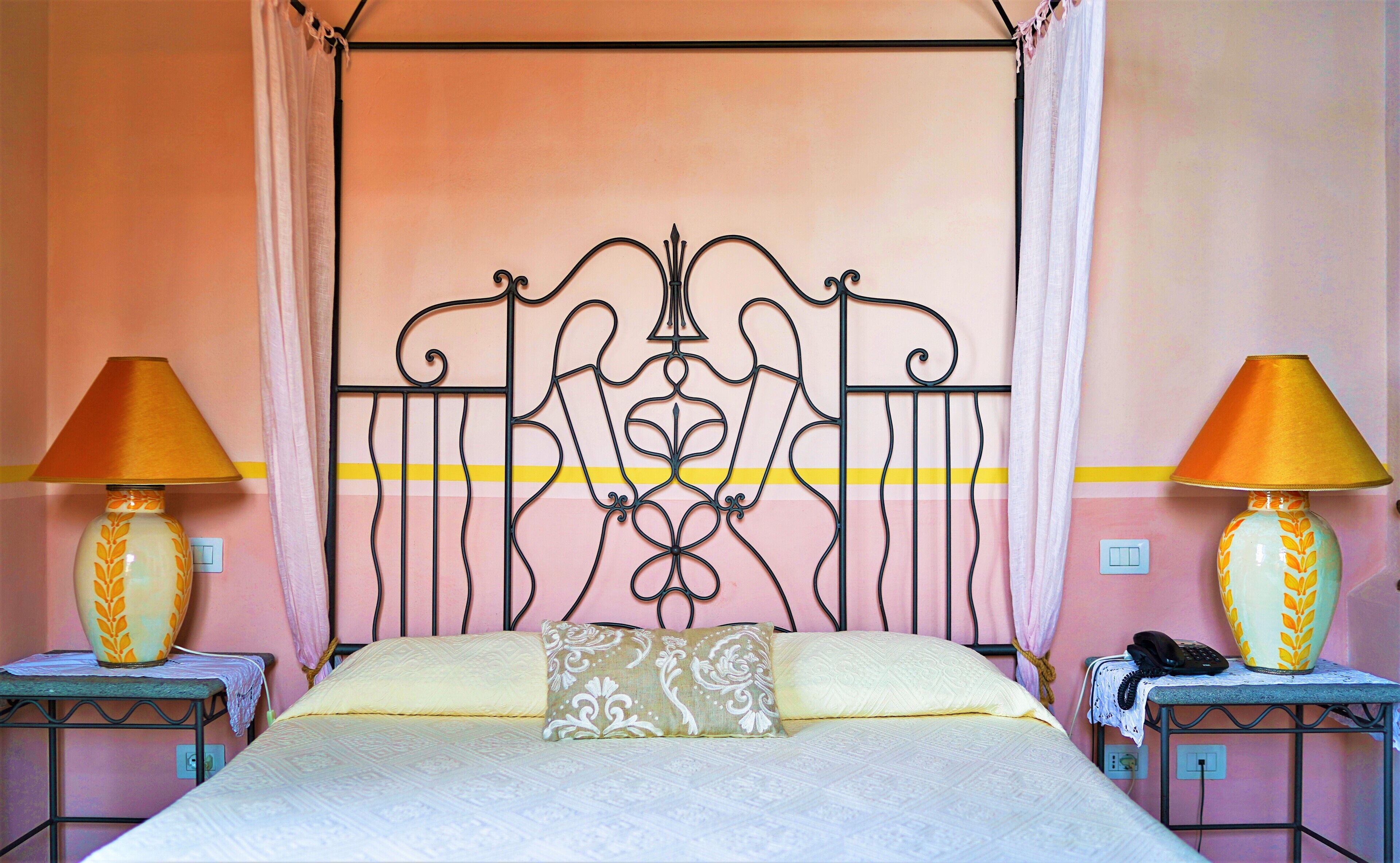 A bedroom with a bed, two bedside tables, lamps, a telephone, and a power outlet.