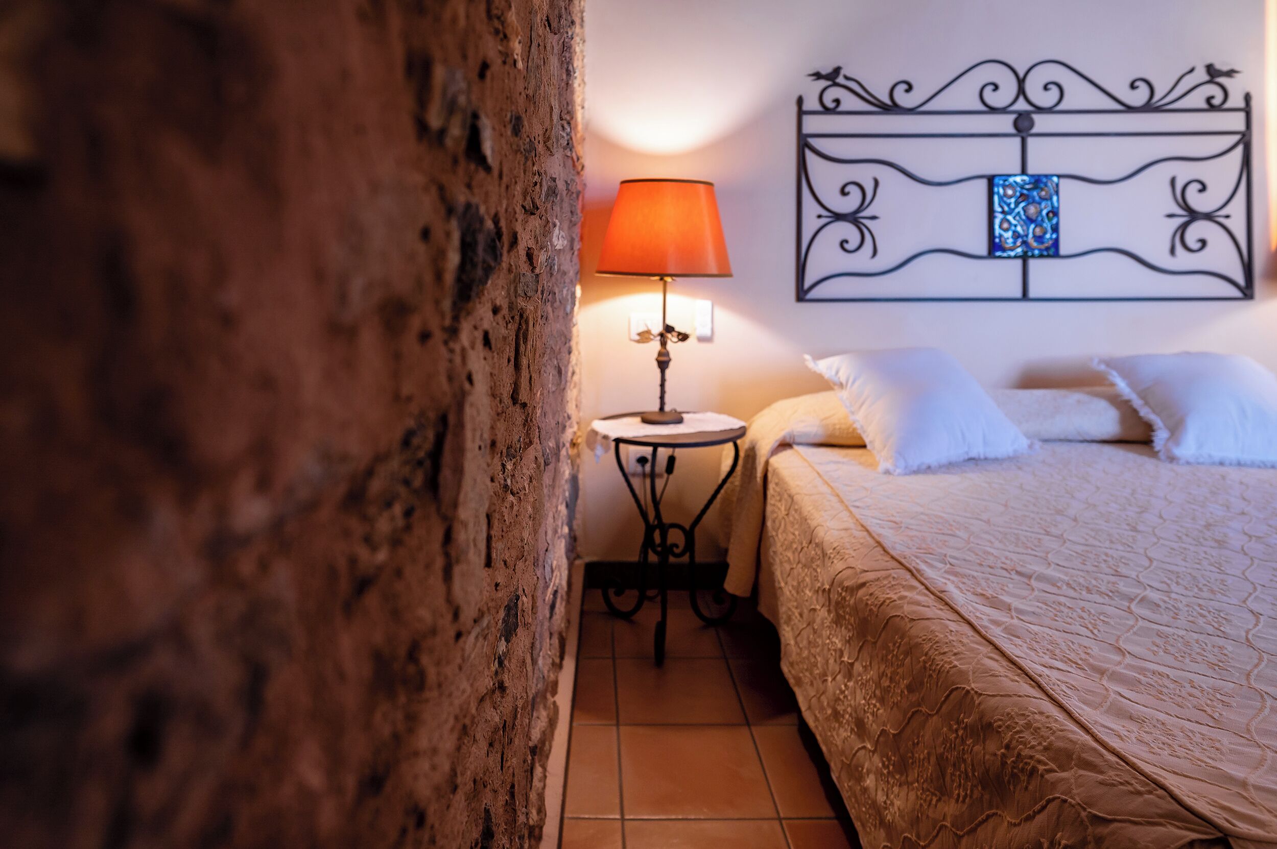 A bedroom with a bed, a nightstand, a lamp, and a decorative headboard.