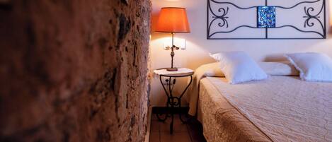 A bedroom with a bed, a nightstand, a lamp, and a decorative headboard.