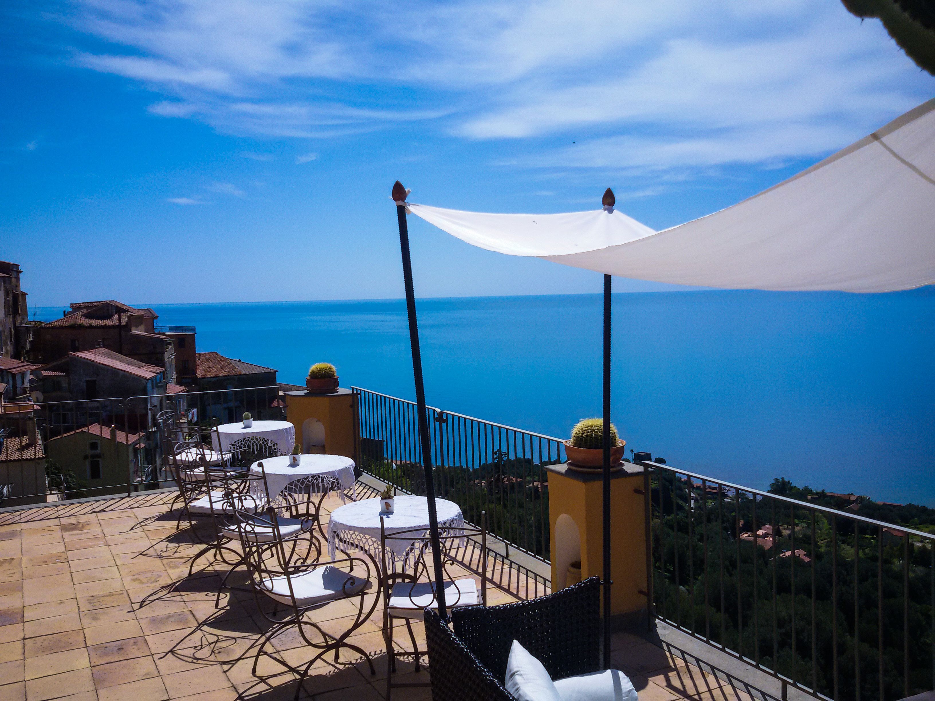 Una terraza con asientos al aire libre, vista al mar y un toldo blanco.