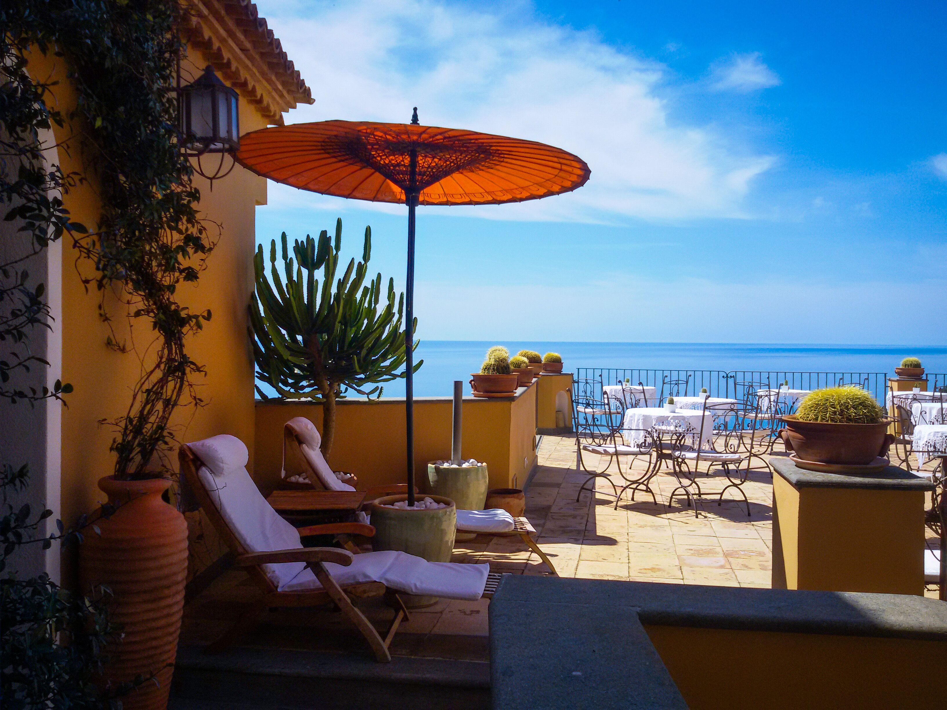 Una terraza con sillones, una mesa y plantas en macetas.