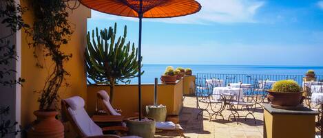 Una terraza con sillones, una mesa y plantas en macetas.