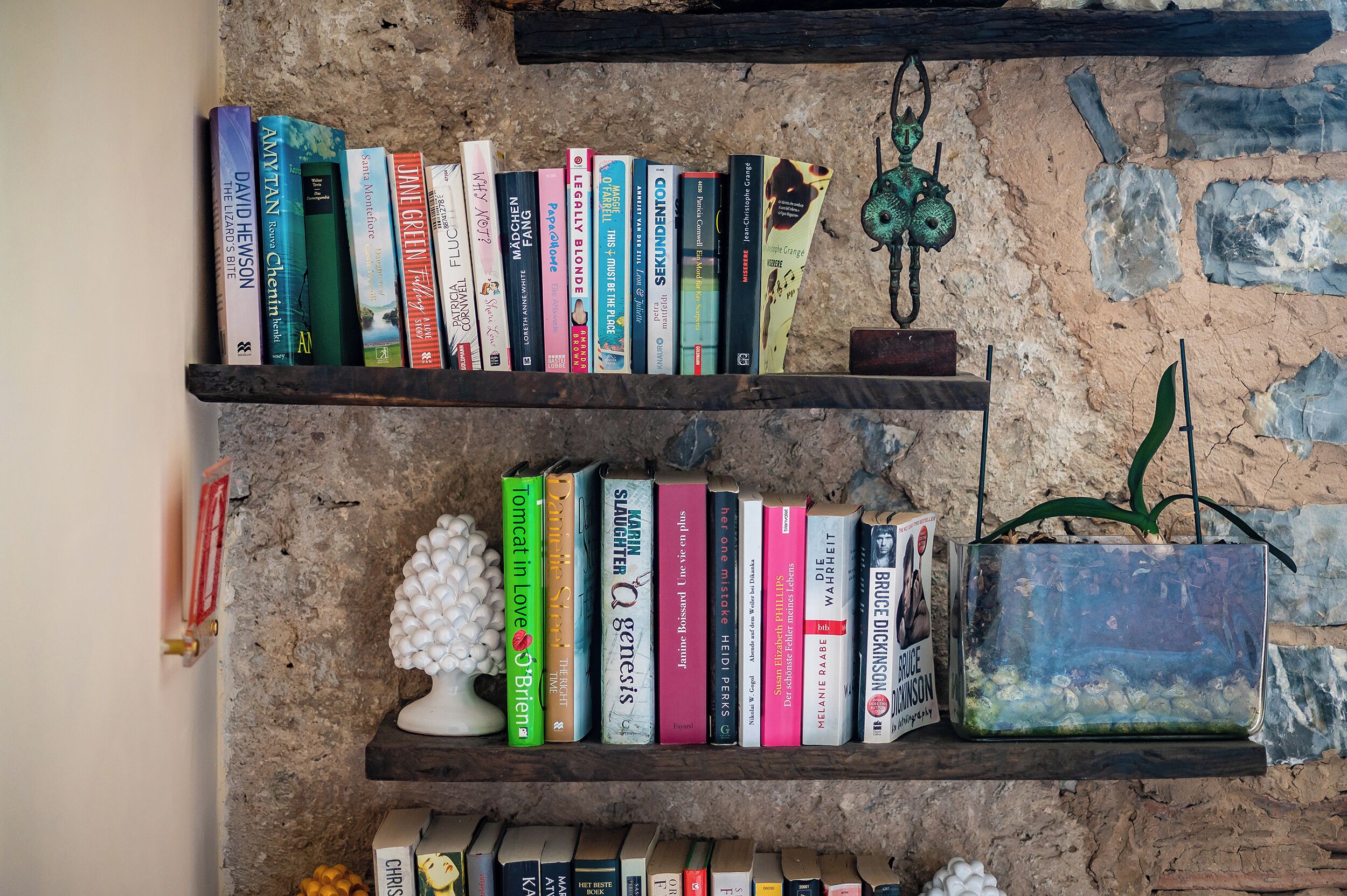 Deux étagères en bois, remplies de livres, sont adossées à un mur à la texture particulière.