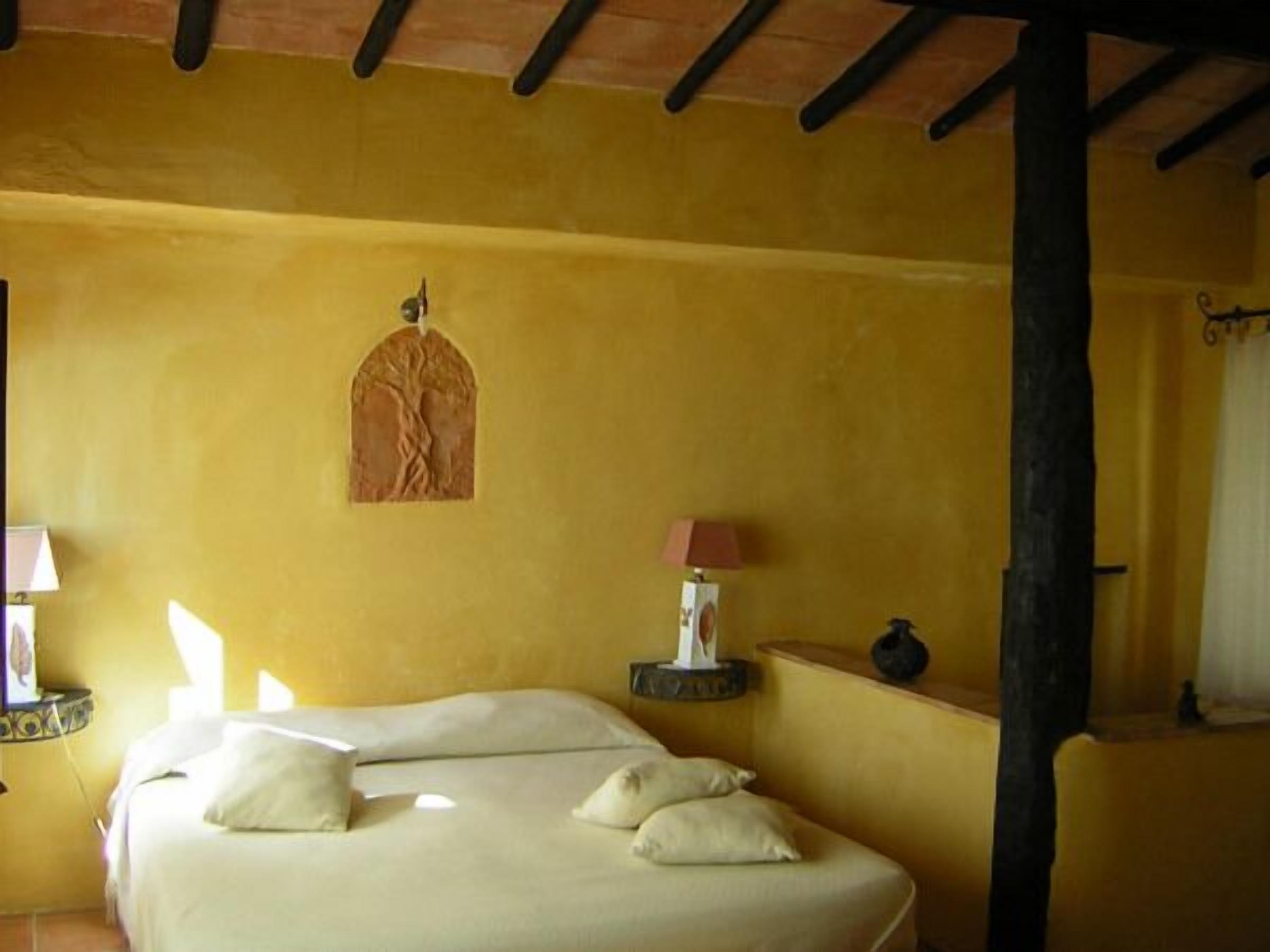 A room with a bed, a lamp, and a small table.