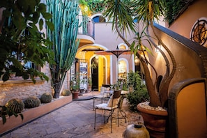A courtyard with a table and chairs, surrounded by cacti and potted plants. - Marulivo Hotel (Pisciotta)