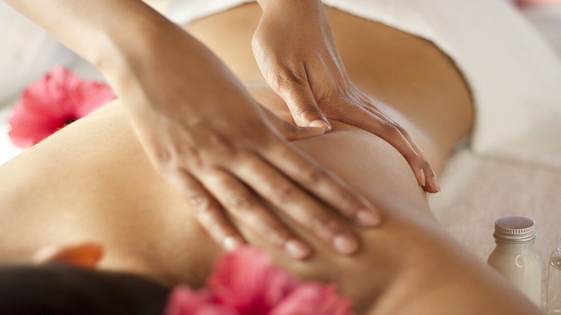 A close-up of hands performing a massage on a person's back.