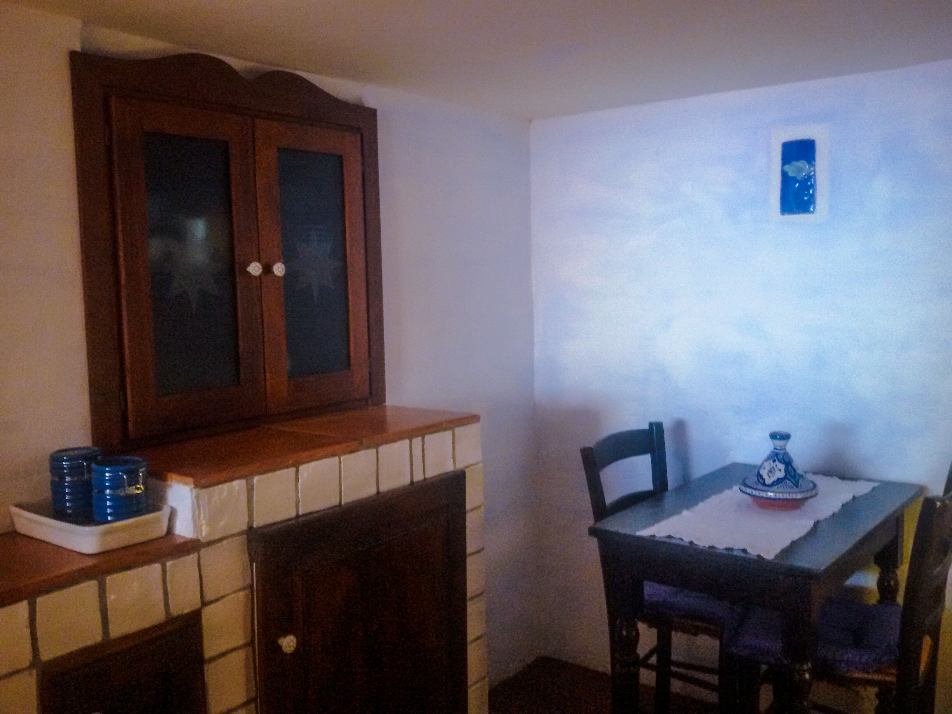 Ein Essbereich mit einem Holzkabinett, einer gefliesten Rückwand und einem Tisch mit Stühlen.
