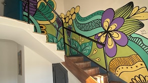 A staircase with a wooden handrail and a colorful mural on the wall. - Gorilla - Hostel (Mendoza)