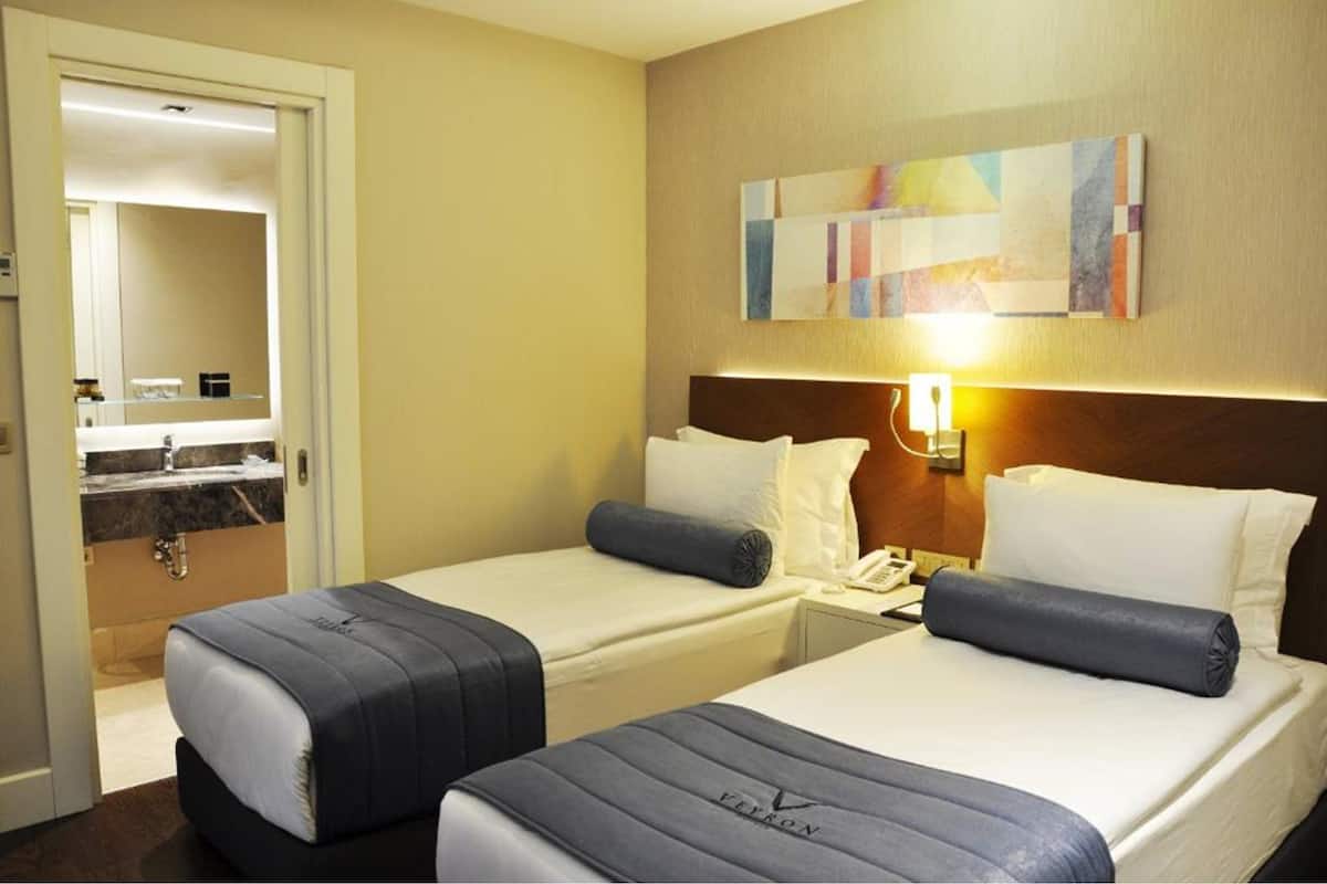 Una habitación de hotel con dos camas, un baño y un cuadro en la pared.