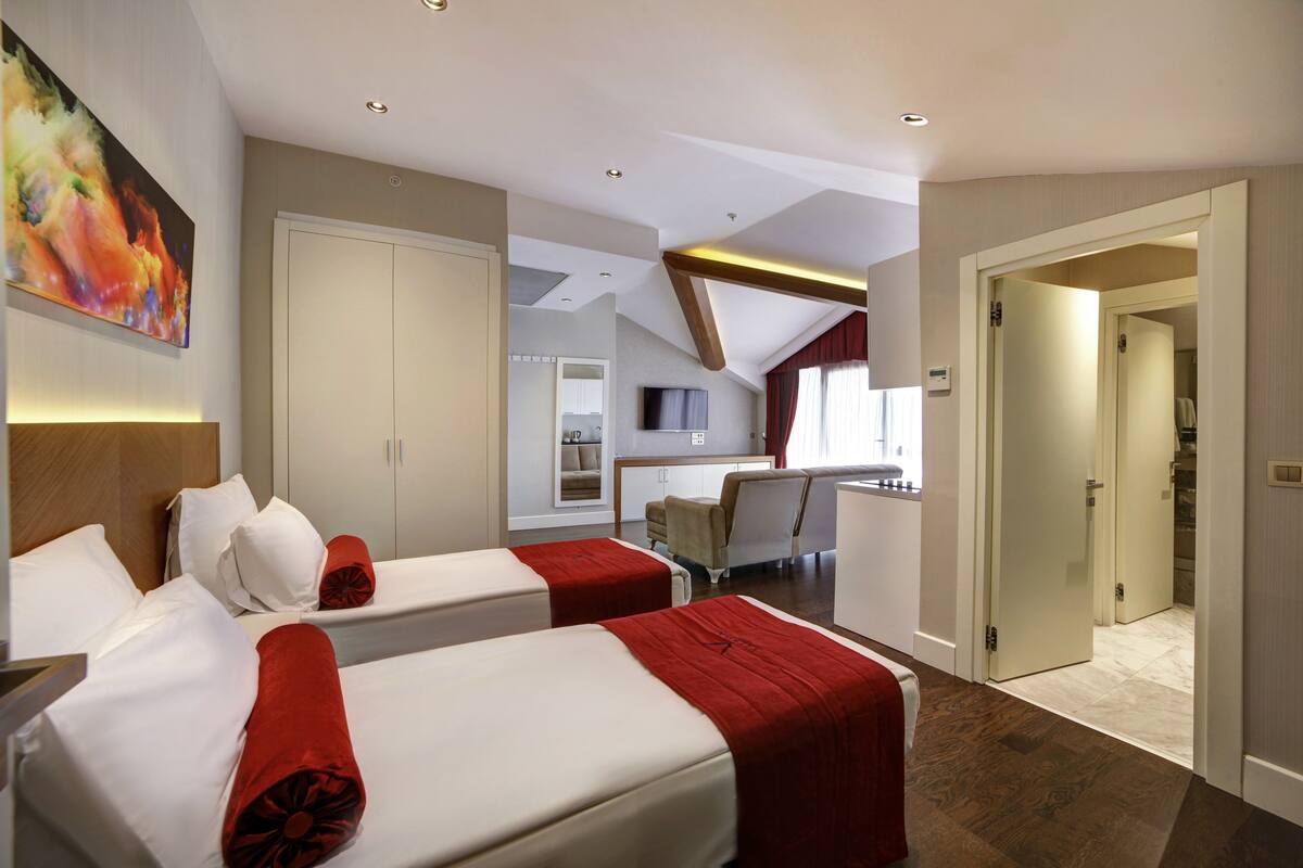 Una habitación de hotel con dos camas, un escritorio, una silla y un televisor.