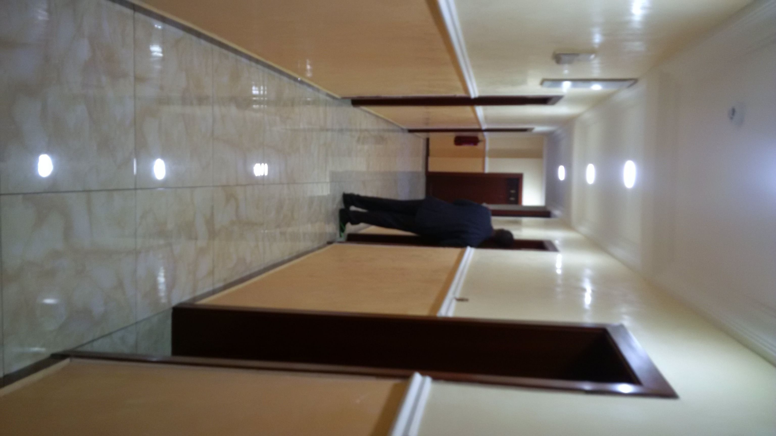 A corridor with tiled walls and a person lying on the floor.