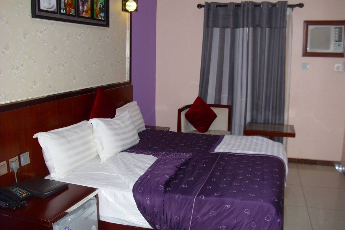Ein Hotelzimmer mit Bett, Nachttisch, Schreibtisch und Stuhl.