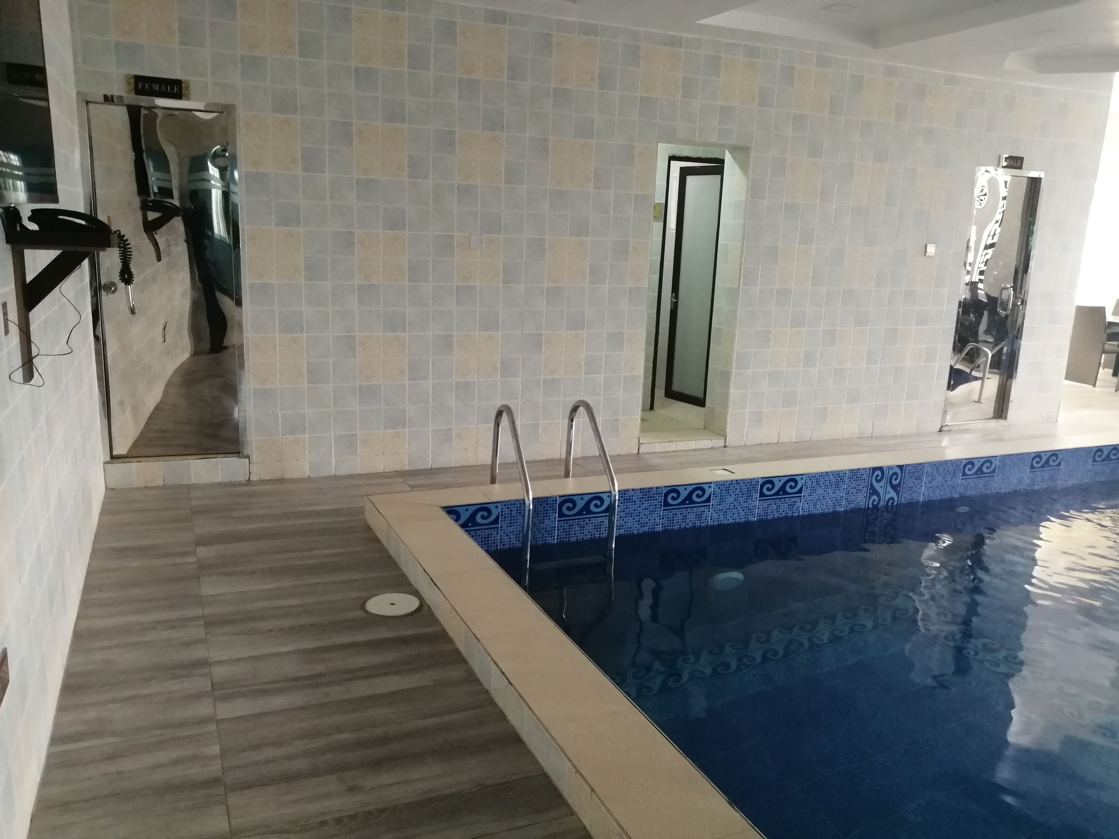 A swimming pool with a tiled border, a shower area, and a door labeled "FEMALE".
