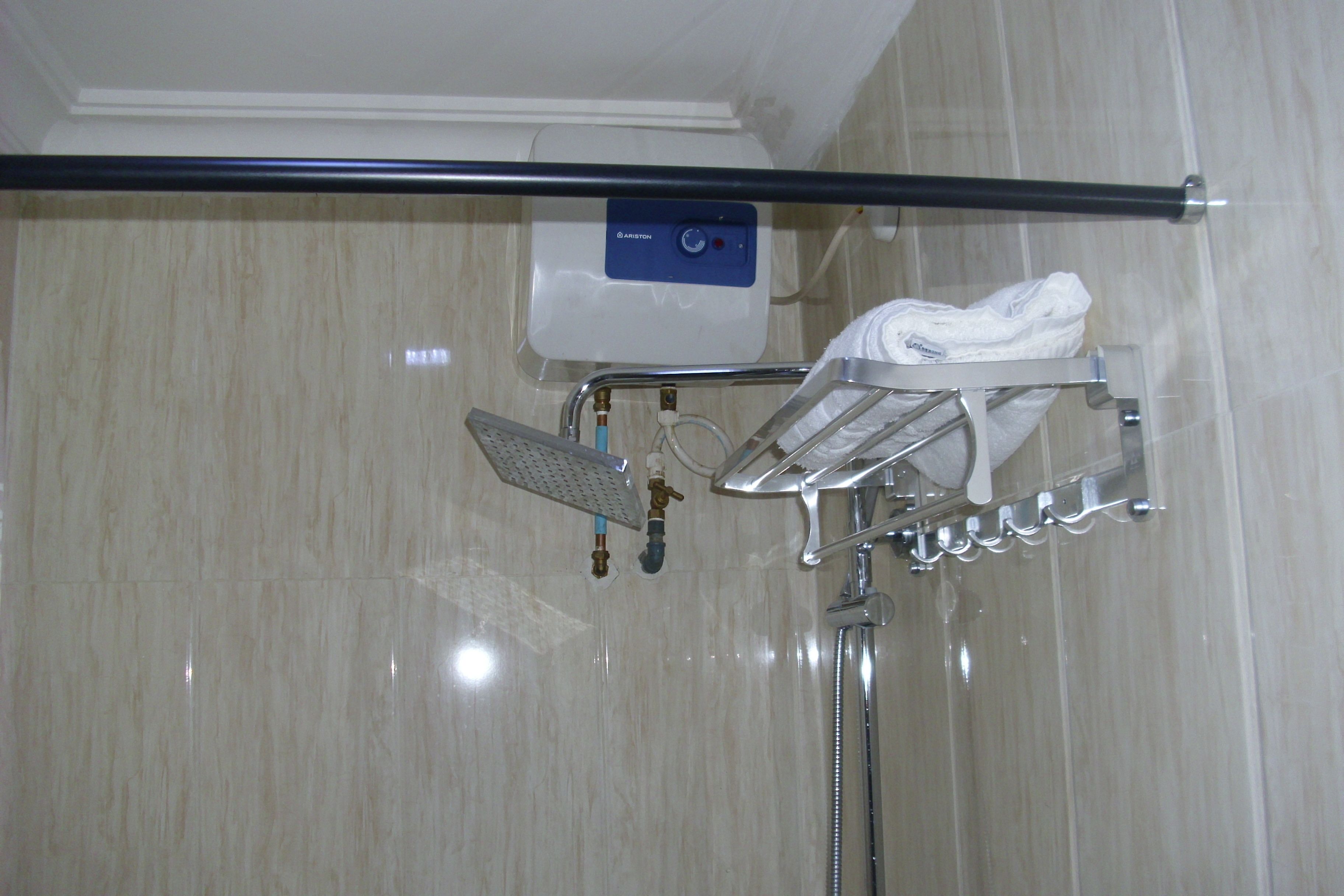 A bathroom with a shower, a towel rack, and a control panel.