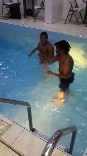 A swimming pool with two people in the water. - GrandVenice Transit Apartments (Lagos)