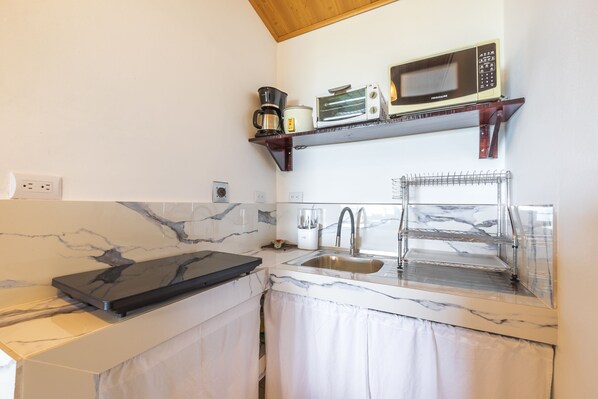 Una cocina con encimera de mármol, un fregadero, microondas, tostadora y cafetera.