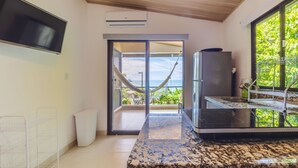 Une cuisine moderne dotée d’un plan de travail en granit, d’une cuisinière encastrée et d’une grande fenêtre donnant sur un balcon où se trouve un hamac.