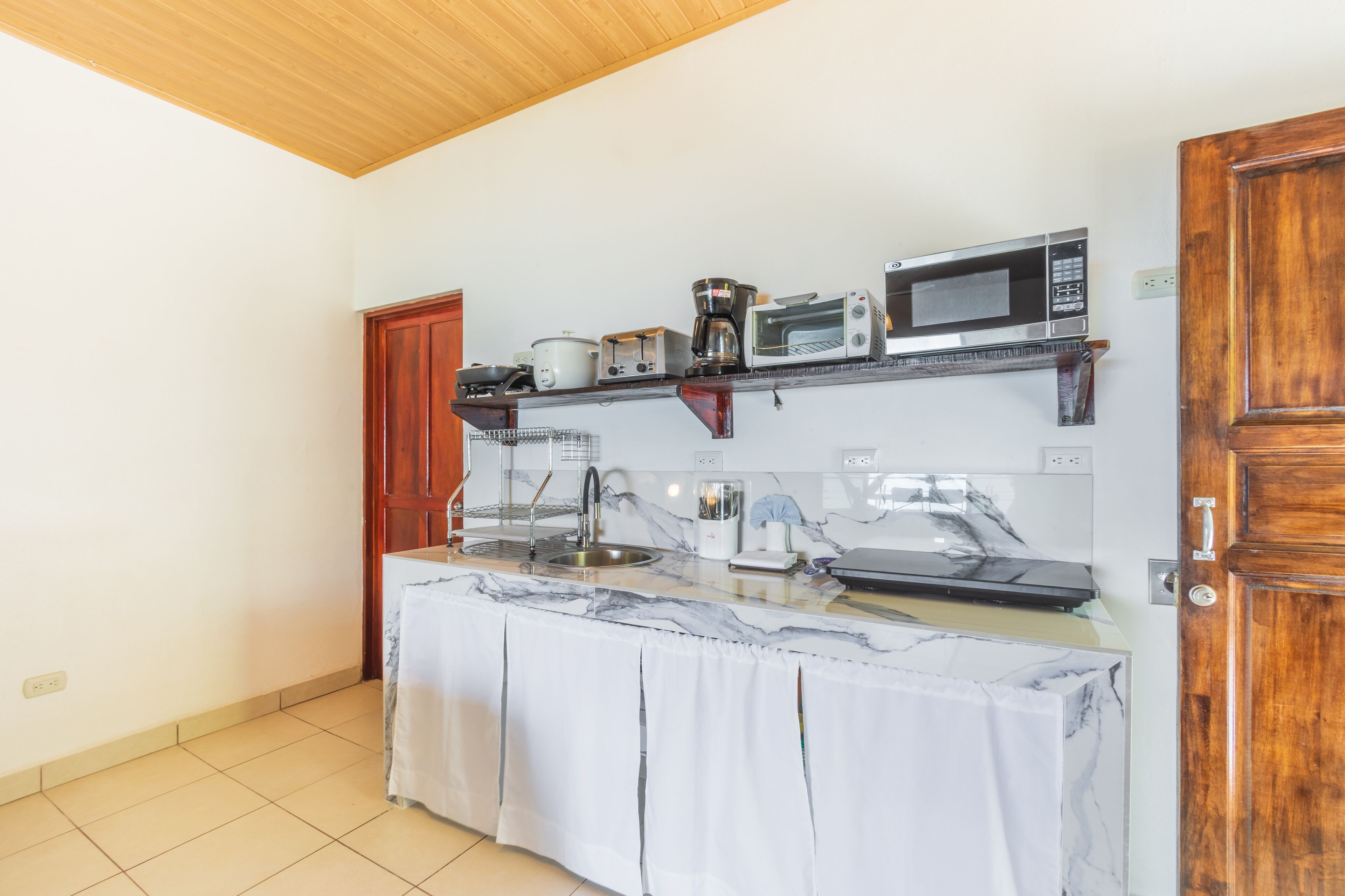 A kitchen with a marble countertop, a coffee maker, a microwave, and a toaster.