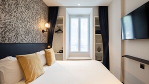 Habitación de hotel moderna con una cama grande, televisión de pantalla plana, armario y ventana con cortinas.
