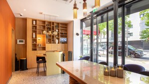 Un interior moderno con una mesa de mármol, estantes de madera y vistas a la calle.