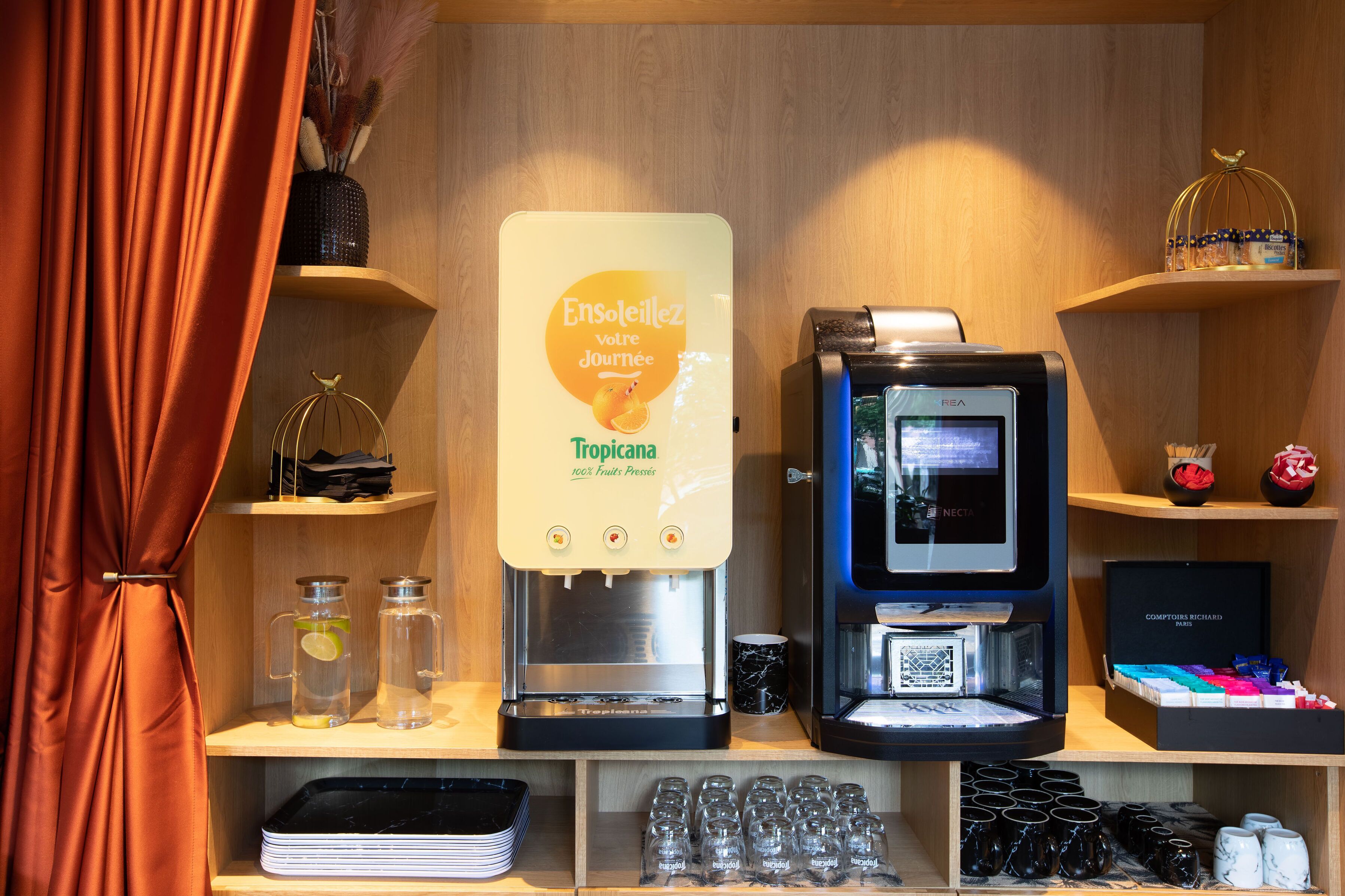 Una estación de café con dispensador de agua, máquina de café y estantes con diversos artículos.