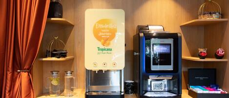 Una estación de café con dispensador de agua, máquina de café y estantes con diversos artículos.