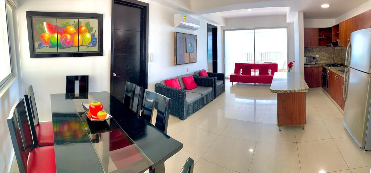 A modern living room with a dining area, a kitchen, and a red sofa.