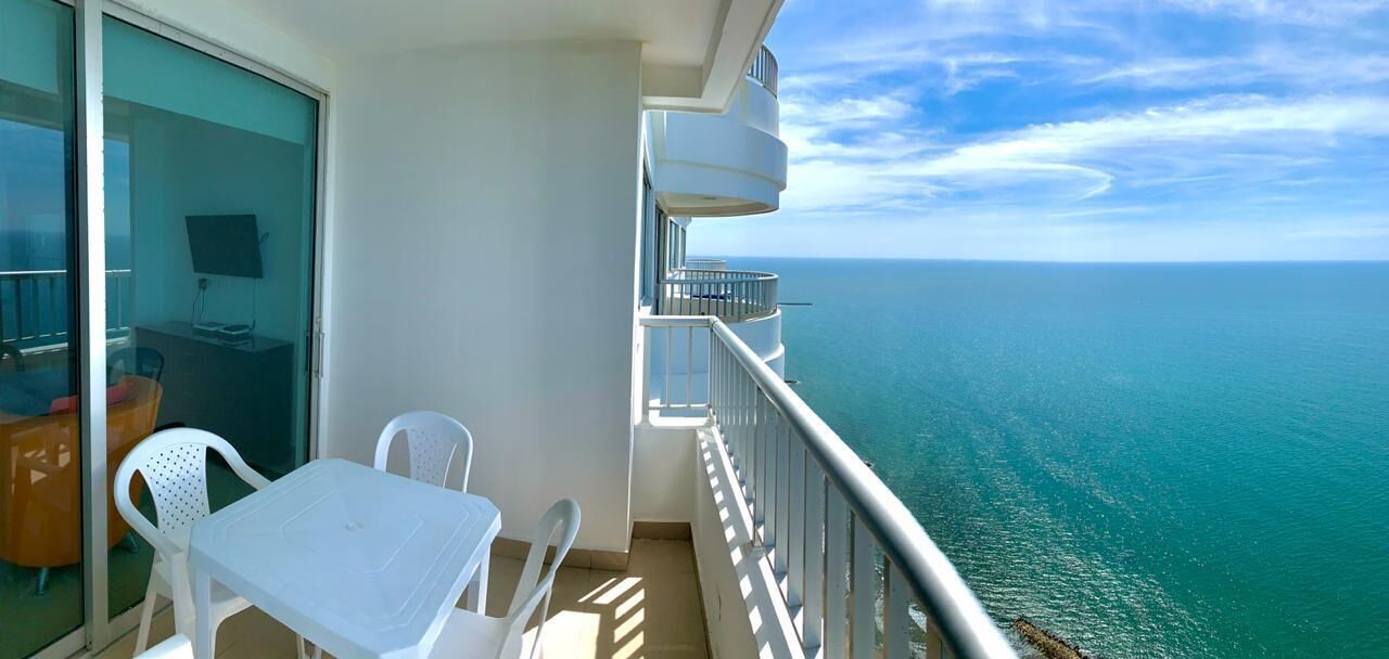 Un balcon avec une table et des chaises, donnant sur la mer.