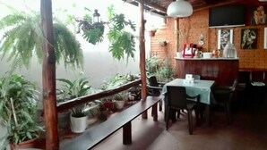 A restaurant with a view, featuring a wooden bench, tables, chairs, potted plants, and a brick wall. - Hotel Santamaria (Alajuela)