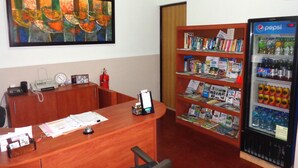 A reception desk with a telephone, a fire extinguisher, and a bookcase filled with magazines. - Hotel Santamaria (Alajuela)