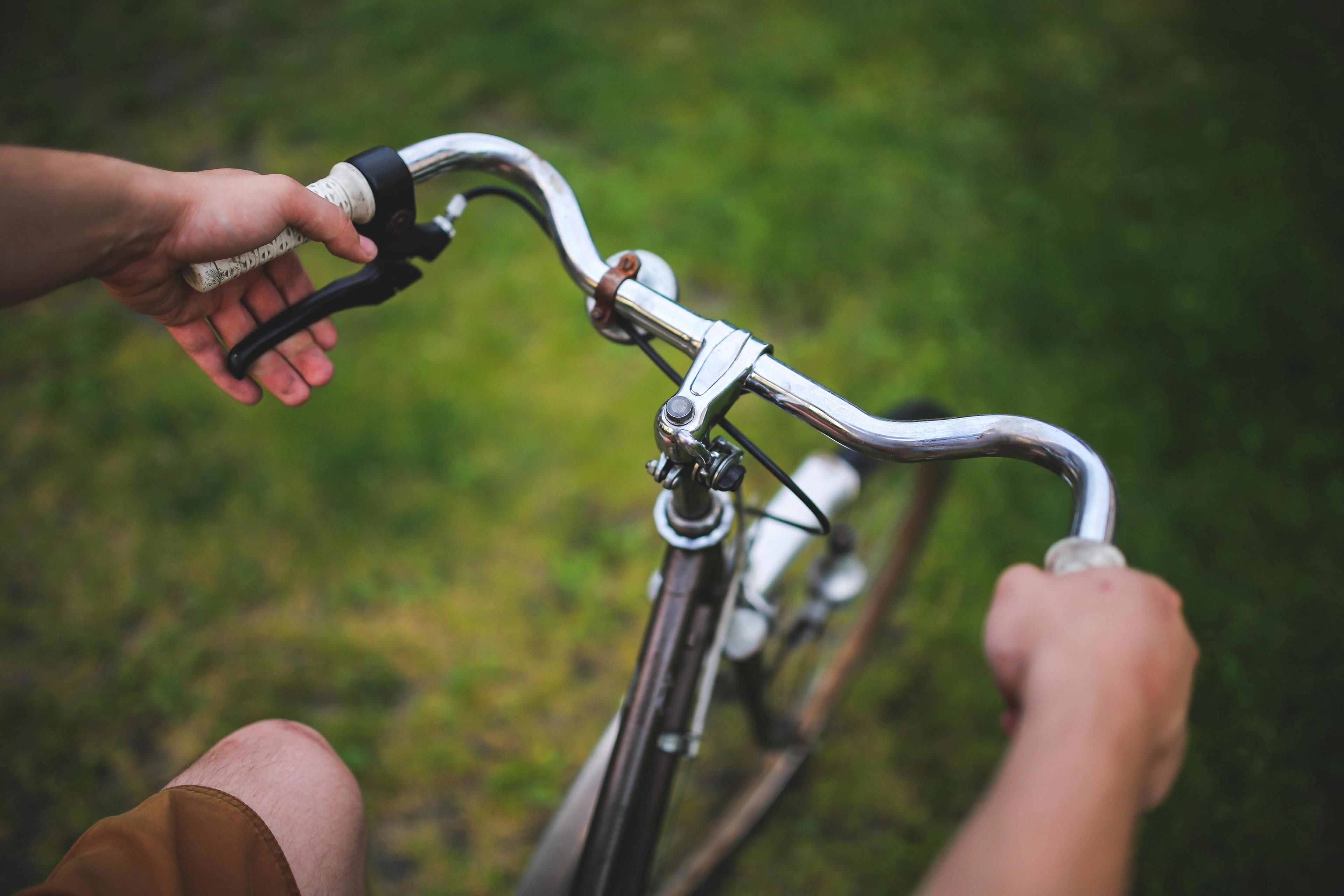 Dettaglio di un manubrio di bicicletta con una mano che lo afferra.