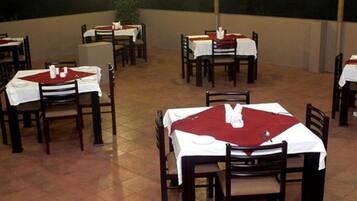 A restaurant with multiple tables and chairs, each covered with a white tablecloth and red placemats.