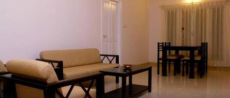 A living room with a sofa, a coffee table, and a dining table with chairs.