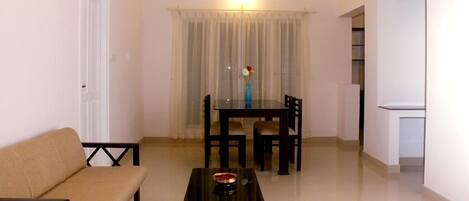 A living room with a sofa, a dining table with chairs, and a small table with a decorative item.