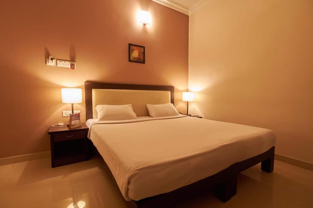 Ein Hotelzimmer mit einem großen Bett, zwei Nachttischlampen, einem Nachttisch und einer Wandleuchte.