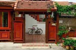 A traditional wooden entrance with a bicycle parked inside. - Huenchandee (Chiang Rai)