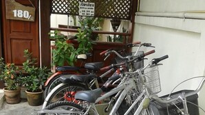 A row of bicycles parked outside a building with a wooden door labeled "180". - Huenchandee (Chiang Rai)