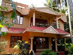 A two-story house with a balcony, large windows, and a red-tiled roof.