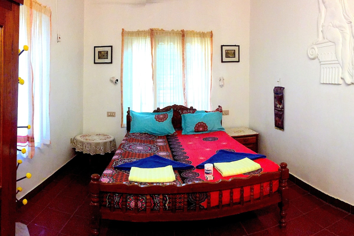 A room with a bed, a small table, and a window with curtains.