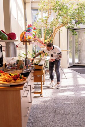Une personne servant des plats dans un buffet proposant une variété de mets et agrémenté de décorations colorées.