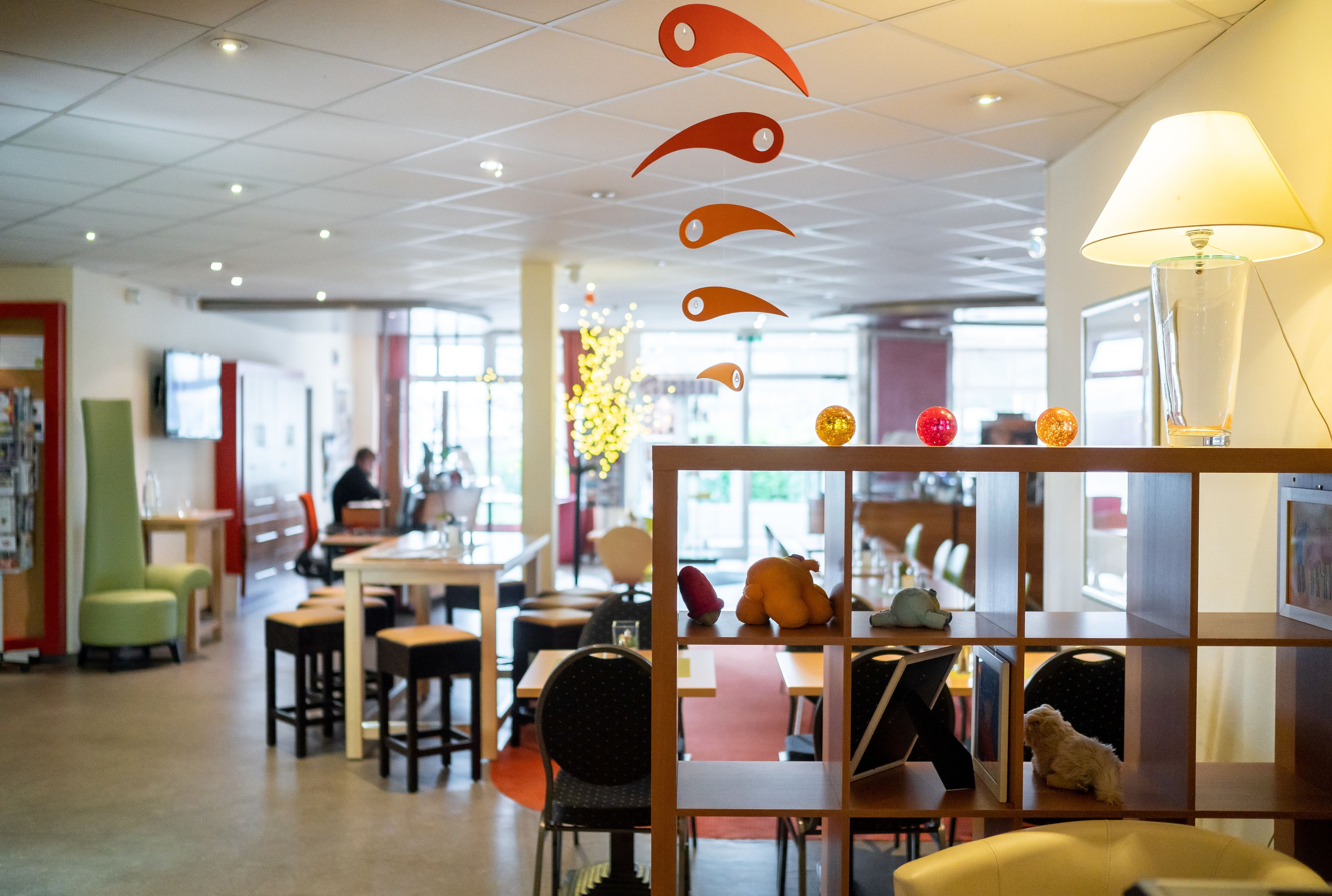 A modern interior with a seating area, tables, and a decorative wall with hanging ornaments.