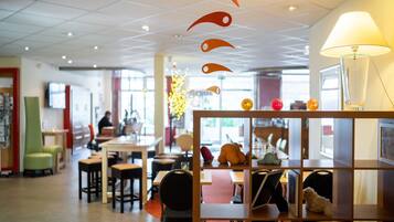 A modern interior with a seating area, tables, and a decorative wall with hanging ornaments.