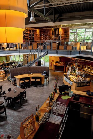 A spacious restaurant with a mezzanine level, a bar area, and a seating area with tables and chairs. - ANDERS Hotel Walsrode (Walsrode)