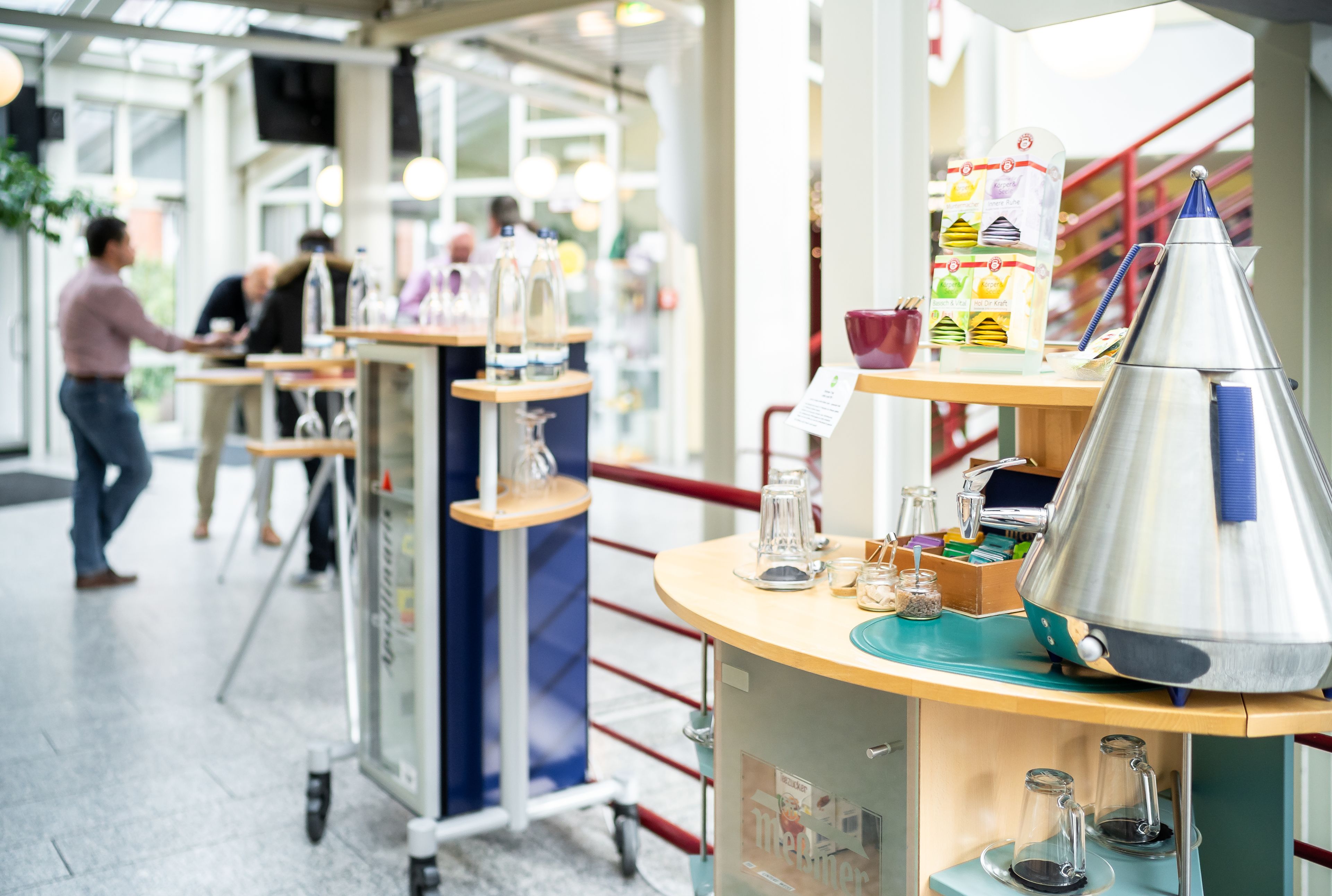 A café with a counter, a menu stand, and a coffee machine.