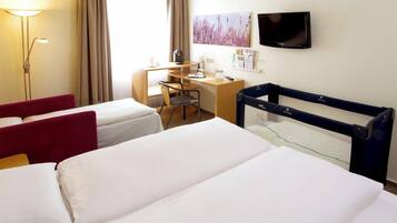 A hotel room with two beds, a desk, a chair, a TV, and a window with curtains.