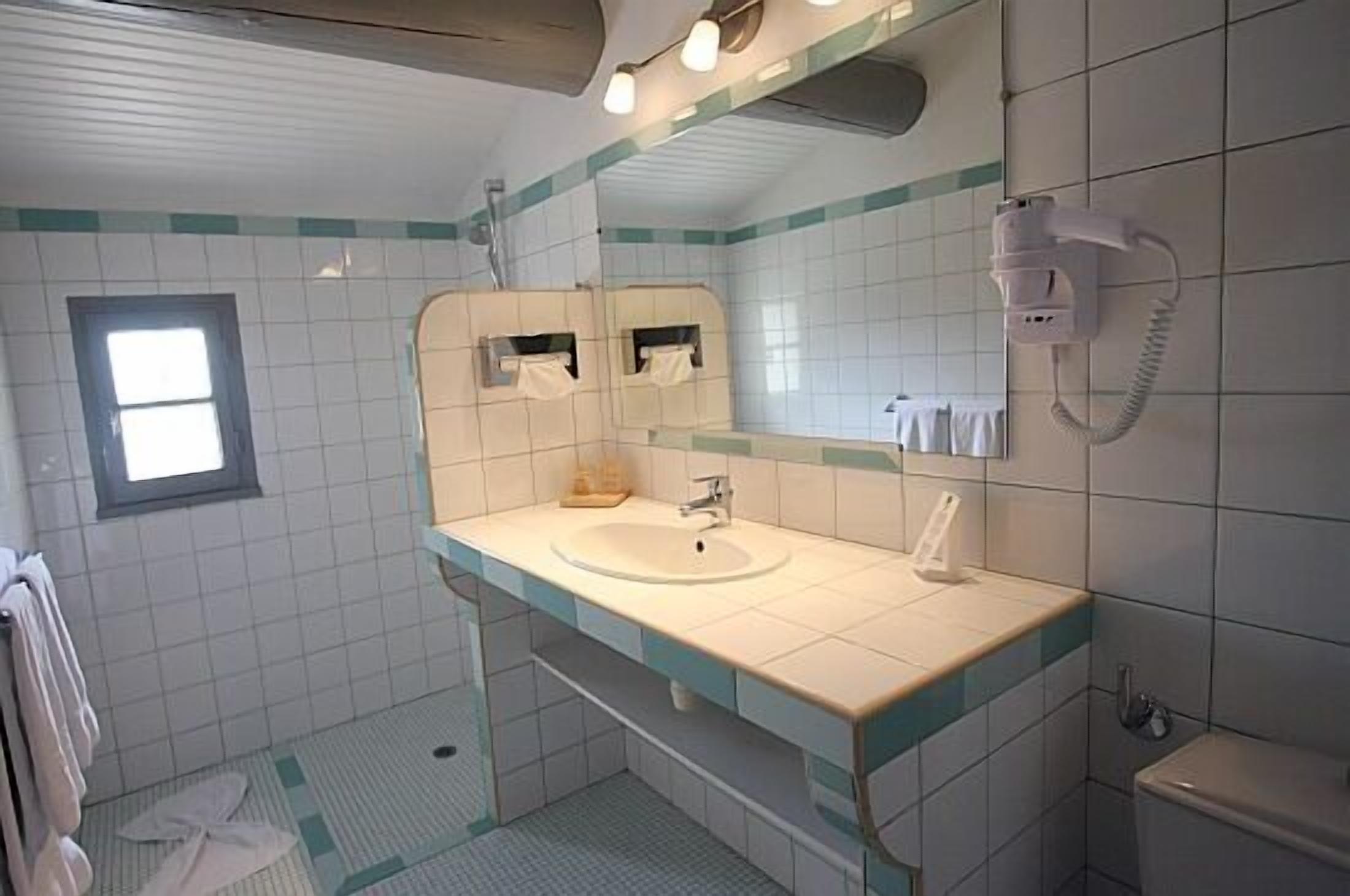 Une salle de bain équipée d’un lavabo, d’un miroir, d’un porte-serviettes et d’un téléphone.