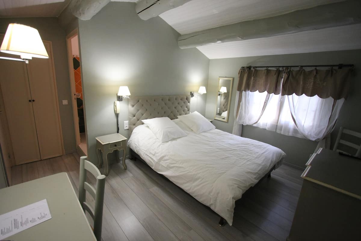 A bedroom with a bed, bedside tables, a desk, a chair, a wardrobe, and a mirror.