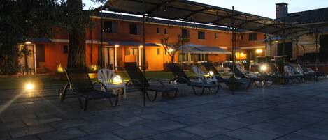 A patio area with sun loungers and a covered seating area, likely part of a hotel or resort.
