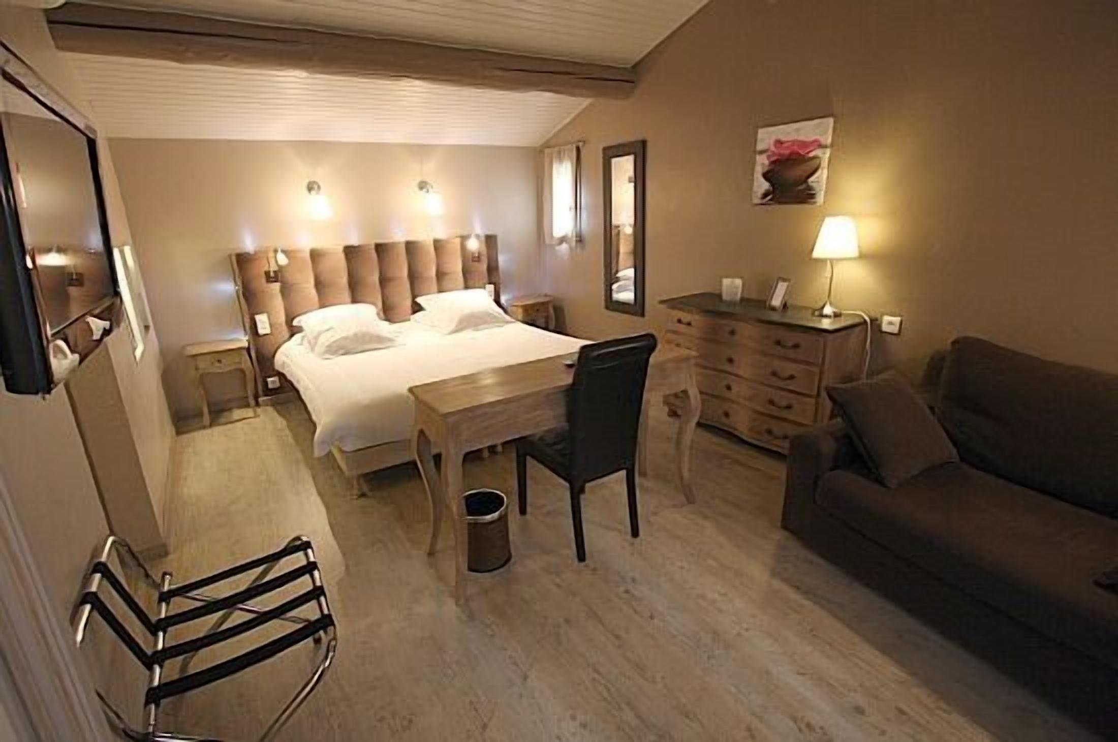 Une chambre d’hôtel équipée d’un lit, d’un bureau, d’une chaise, d’un canapé et d’une poubelle.